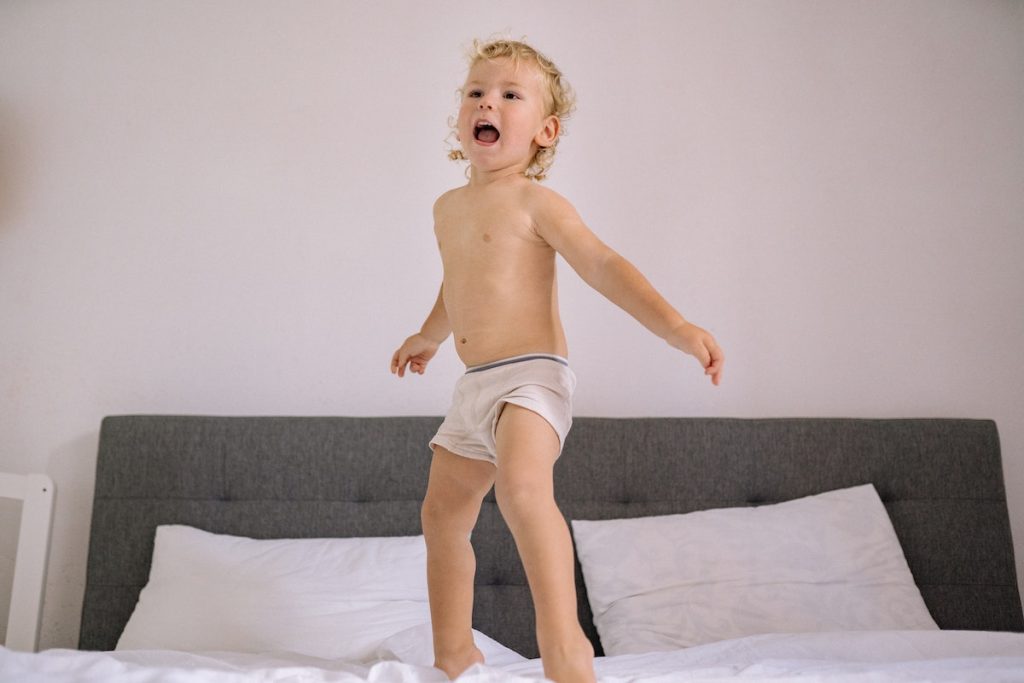 Happy Child Jumping on Bed at Home